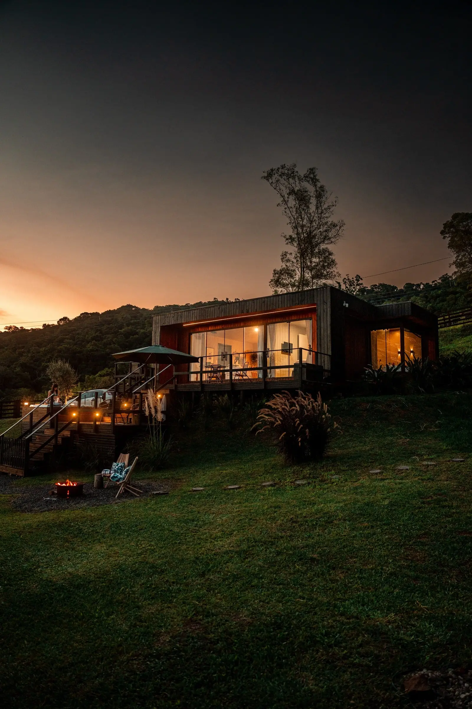 Casa Origem do Lote 11 iluminada ao entardecer, cercada pela natureza